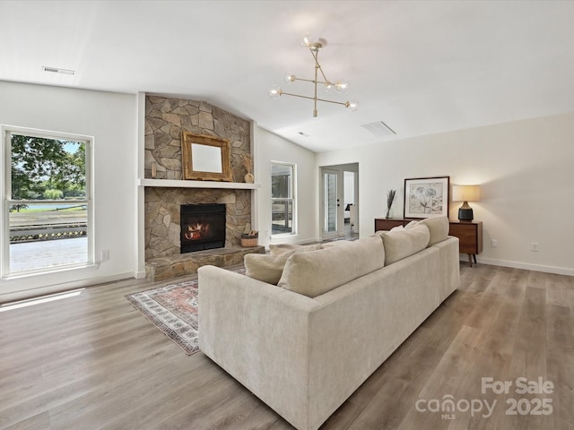 3531 Bon Rea Dr, Charlotte, NC 28226 - living area featuring lofted ceiling, a chandelier, light wood-style floors, a stone fireplace, and baseboards