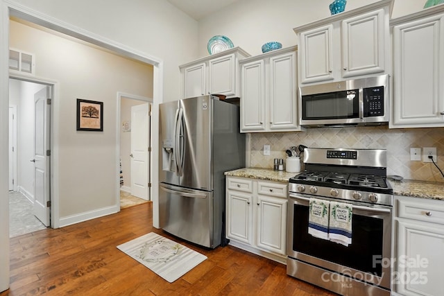 141 Tall Fern Loop, Mooresville, NC 28117 - kitchen featuring stainless steel appliances, decorative backsplash, dark wood-type flooring, light stone counters, and baseboards