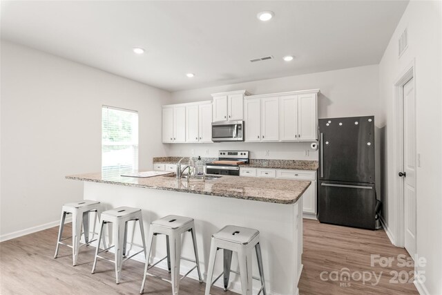 2340 Lanza Dr, Charlotte, NC 28215 - kitchen with stainless steel appliances, a kitchen bar, white cabinets, and recessed lighting