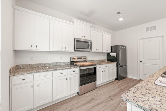 2340 Lanza Dr, Charlotte, NC 28215 - kitchen with appliances with stainless steel finishes, white cabinetry, light wood-style floors, baseboards, and light stone counters
