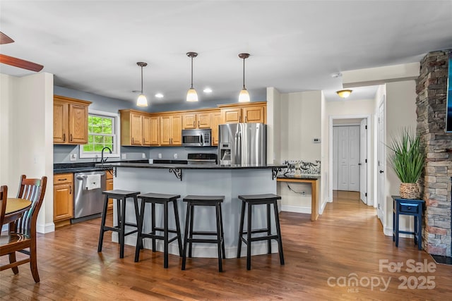 32 Evita Cove Rd, Weaverville, NC 28787 - kitchen with stainless steel appliances, dark countertops, dark wood finished floors, a breakfast bar area, and a kitchen island