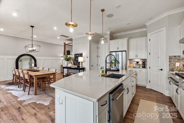 20216 Shaffer Bach Ln, Charlotte, NC 28277 - kitchen with a sink, appliances with stainless steel finishes, wood finished floors, ornamental molding, and tasteful backsplash