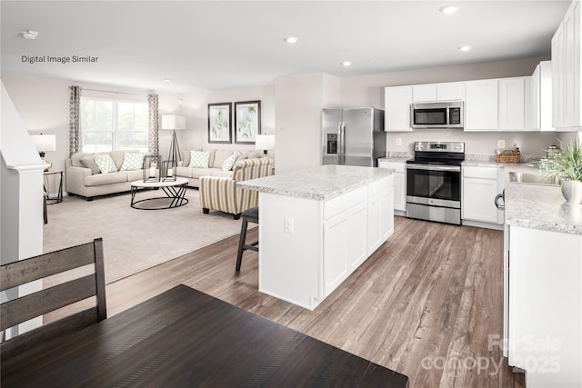 202 Rose Ln Unit 1501, Pageland, SC 29728 - kitchen with stainless steel appliances, open floor plan, a center island, light wood-style floors, and white cabinets
