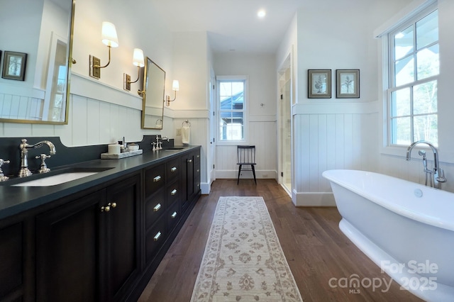 2270 New Gray Rock Rd, Fort Mill, SC 29708 - bathroom featuring wainscoting, double vanity, a freestanding bath, wood finished floors, and a decorative wall