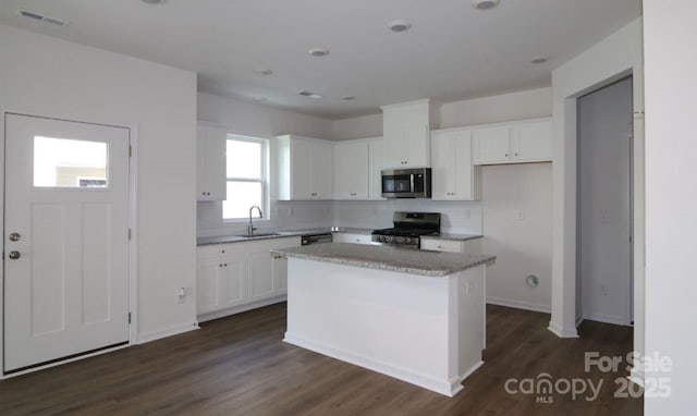 1922 Highland Park Dr, Charlotte, NC 28269 - kitchen with stainless steel appliances, a sink, white cabinets, and decorative backsplash