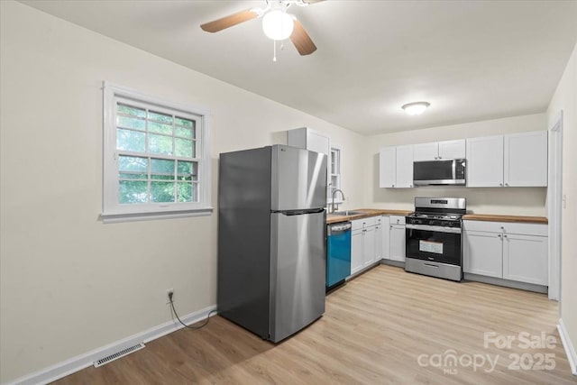 818 Stowe Ln, Gastonia, NC 28056 - kitchen with appliances with stainless steel finishes, light wood finished floors, baseboards, and white cabinetry