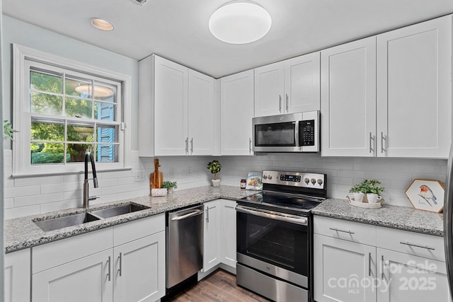 3308 Selwyn Farms Ln Unit 5, Charlotte, NC 28209 - kitchen with stainless steel appliances, white cabinetry, backsplash, wood finished floors, and light stone countertops