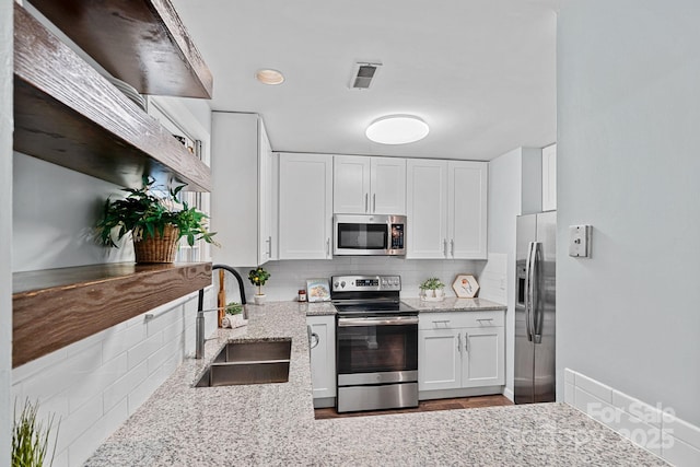 3308 Selwyn Farms Ln Unit 5, Charlotte, NC 28209 - kitchen featuring appliances with stainless steel finishes, decorative backsplash, light stone counters, white cabinets, and wood finished floors