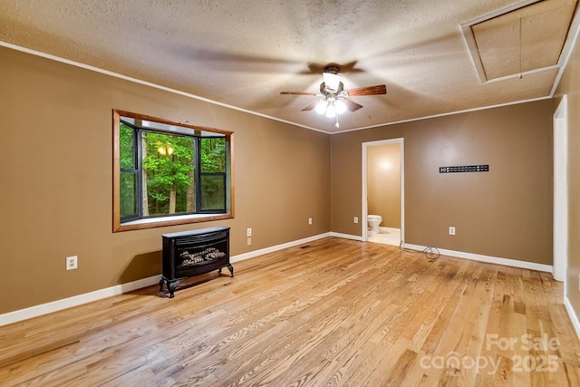 302 Mitchell Rd, Sylva, NC 28779 - unfurnished room with a wood stove, attic access, a ceiling fan, a textured ceiling, and wood finished floors