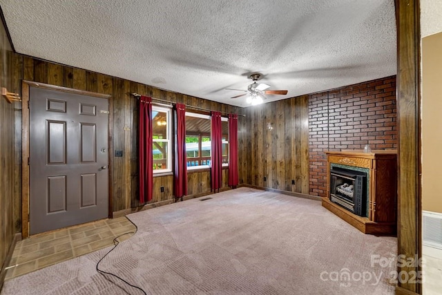 302 Mitchell Rd, Sylva, NC 28779 - unfurnished living room featuring wooden walls, ceiling fan, a brick fireplace, carpet, and a textured ceiling