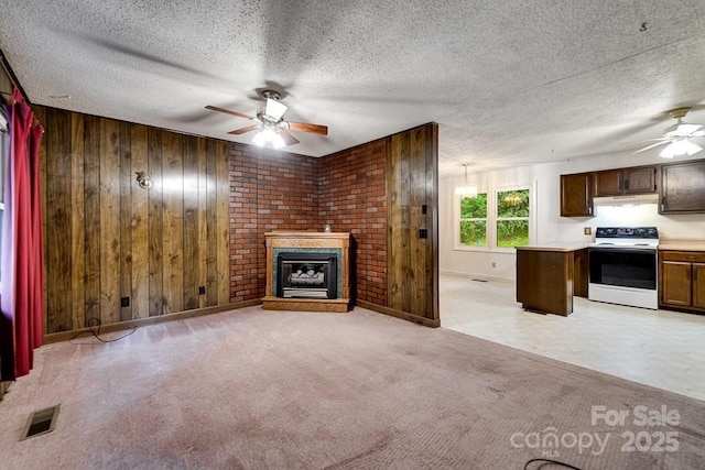302 Mitchell Rd, Sylva, NC 28779 - unfurnished living room featuring ceiling fan, wooden walls, a brick fireplace, baseboards, and a textured ceiling