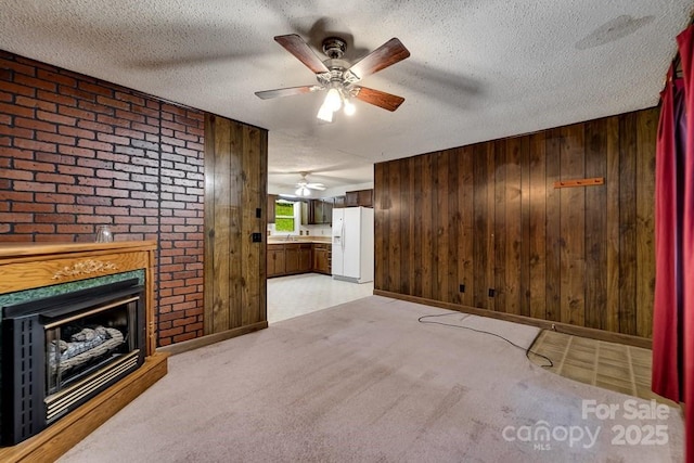 302 Mitchell Rd, Sylva, NC 28779 - unfurnished living room featuring ceiling fan, wood walls, a sink, a fireplace, and baseboards