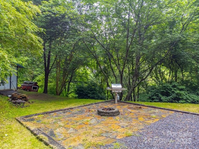 302 Mitchell Rd, Sylva, NC 28779 - view of grassy yard featuring a fire pit, an outdoor structure, and a forest view