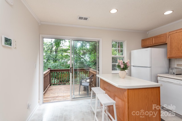 10548 English Setter Way, Charlotte, NC 28269 - kitchen featuring white appliances, ornamental molding, light countertops, a kitchen island, and light wood-style flooring