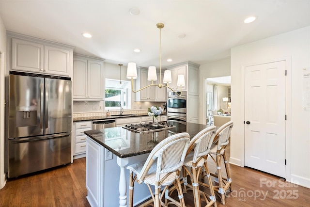 7022 Lancer Dr, Charlotte, NC 28226 - kitchen with stainless steel appliances, dark wood finished floors, a breakfast bar area, decorative backsplash, and dark stone countertops