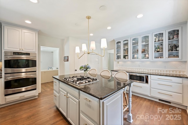 7022 Lancer Dr, Charlotte, NC 28226 - kitchen featuring appliances with stainless steel finishes, white cabinets, glass insert cabinets, light wood-style flooring, and recessed lighting