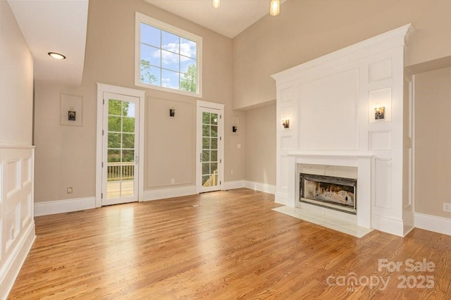 74 Eastmoor Dr, Asheville, NC 28805 - unfurnished living room featuring light wood-style flooring, a fireplace with flush hearth, baseboards, and a high ceiling