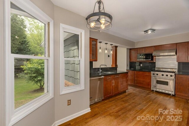 74 Eastmoor Dr, Asheville, NC 28805 - kitchen featuring stainless steel appliances, wall chimney exhaust hood, a sink, dark countertops, and decorative light fixtures