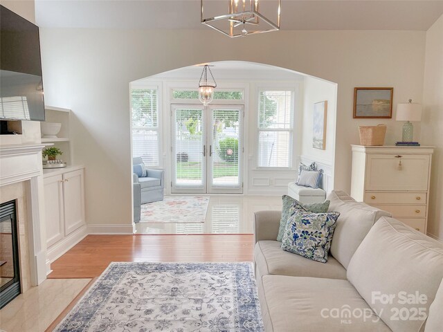 1006 Phar Lap Dr, Indian Trail, NC 28079 - living room featuring a chandelier, light wood finished floors, arched walkways, a premium fireplace, and baseboards