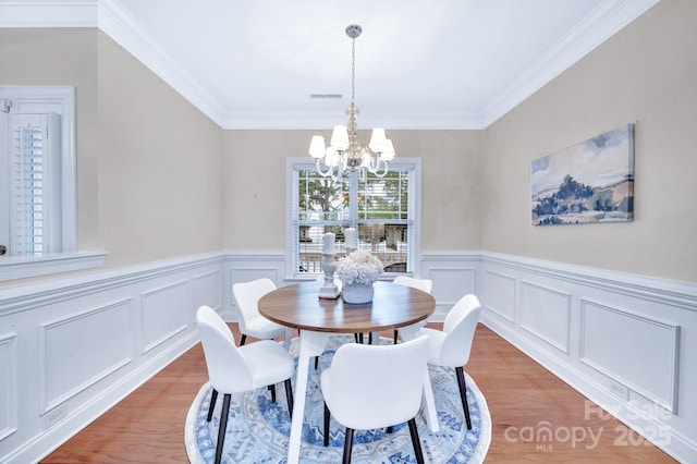 1006 Phar Lap Dr, Indian Trail, NC 28079 - dining room featuring a chandelier, light wood-type flooring, a wainscoted wall, crown molding, and a decorative wall