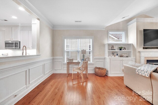 1006 Phar Lap Dr, Indian Trail, NC 28079 - living area featuring light wood finished floors, wainscoting, a fireplace, a decorative wall, and ornamental molding