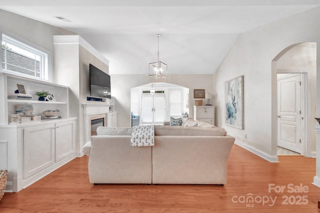 1006 Phar Lap Dr, Indian Trail, NC 28079 - living room with arched walkways, light wood-type flooring, a glass covered fireplace, baseboards, and vaulted ceiling