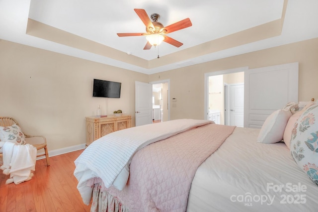 1006 Phar Lap Dr, Indian Trail, NC 28079 - bedroom featuring a raised ceiling, baseboards, light wood-style flooring, ensuite bath, and a ceiling fan