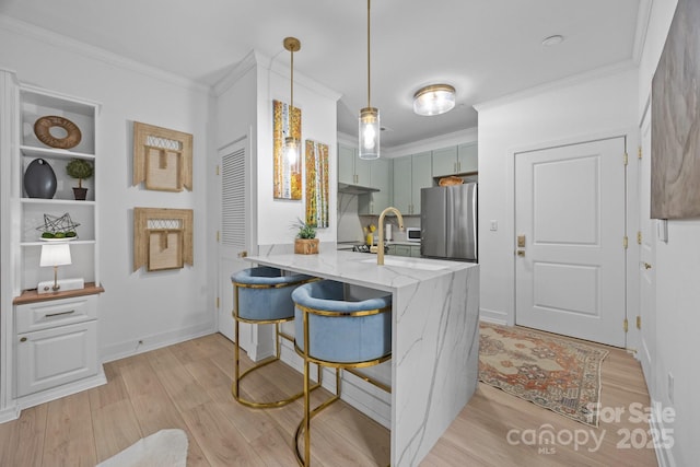 630 Calvert St Unit 111, Charlotte, NC 28208 - kitchen featuring freestanding refrigerator, crown molding, a peninsula, light wood-style floors, and light stone counters