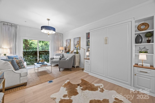 630 Calvert St Unit 111, Charlotte, NC 28208 - living area featuring light wood-type flooring, built in shelves, ornamental molding, and a chandelier