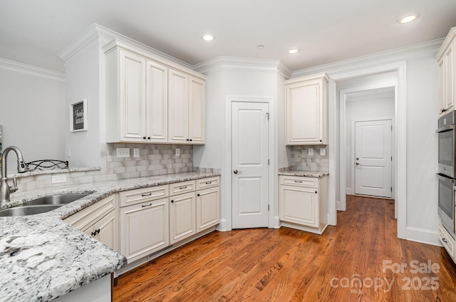 10874 Rise Ln, Fort Mill, SC 29707 - kitchen with a sink, ornamental molding, tasteful backsplash, light stone countertops, and light wood finished floors