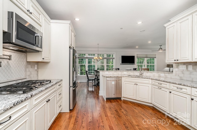 10874 Rise Ln, Fort Mill, SC 29707 - kitchen featuring stainless steel appliances, a sink, a peninsula, ornamental molding, and white cabinets