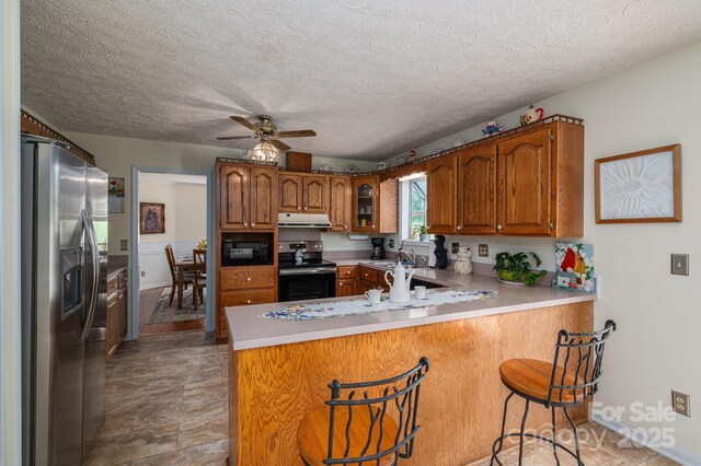 112 Ocean Dr, Shelby, NC 28152 - kitchen featuring appliances with stainless steel finishes, a peninsula, range hood, brown cabinets, and ceiling fan
