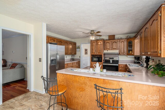 112 Ocean Dr, Shelby, NC 28152 - kitchen featuring appliances with stainless steel finishes, extractor fan, a peninsula, a ceiling fan, and brown cabinets
