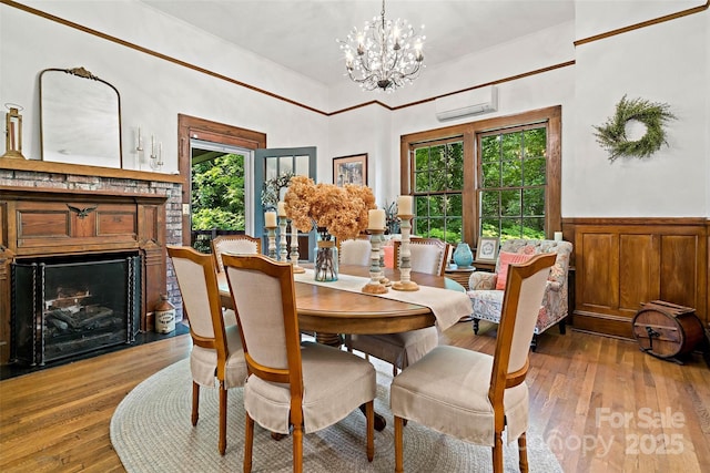 147 Preservation Way, Waynesville, NC 28786 - dining area featuring an AC wall unit, wood-type flooring, a fireplace, a chandelier, and a towering ceiling