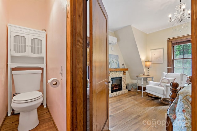 147 Preservation Way, Waynesville, NC 28786 - bathroom featuring wood finished floors, an AC wall unit, toilet, a stone fireplace, and a chandelier
