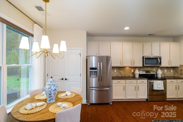 4323 Bright Rd, Charlotte, NC 28214 - kitchen with appliances with stainless steel finishes, a chandelier, dark wood finished floors, backsplash, and white cabinets