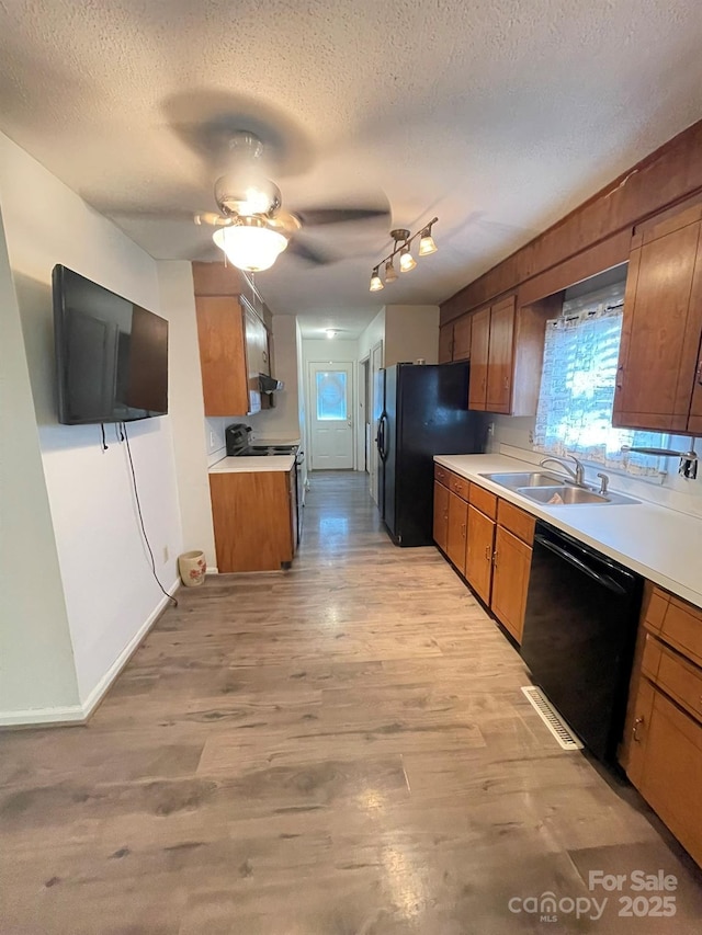 4317 Waxhaw Indian Trail Rd, Indian Trail, NC 28079 - kitchen featuring black appliances, a textured ceiling, brown cabinetry, a sink, and light countertops