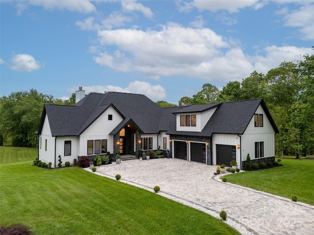 38 Thistle Ln, Fletcher, NC 28732 - modern farmhouse style home featuring decorative driveway, board and batten siding, a front yard, a chimney, and a garage