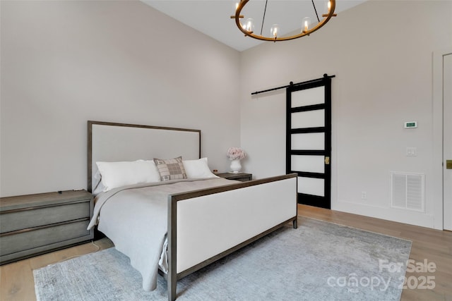 38 Thistle Ln, Fletcher, NC 28732 - bedroom with a chandelier, wood finished floors, and a barn door