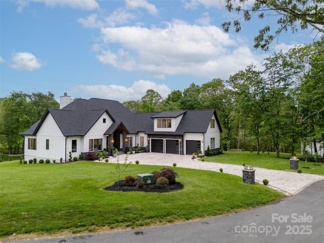 38 Thistle Ln, Fletcher, NC 28732 - modern inspired farmhouse with curved driveway, a front yard, an attached garage, a chimney, and board and batten siding