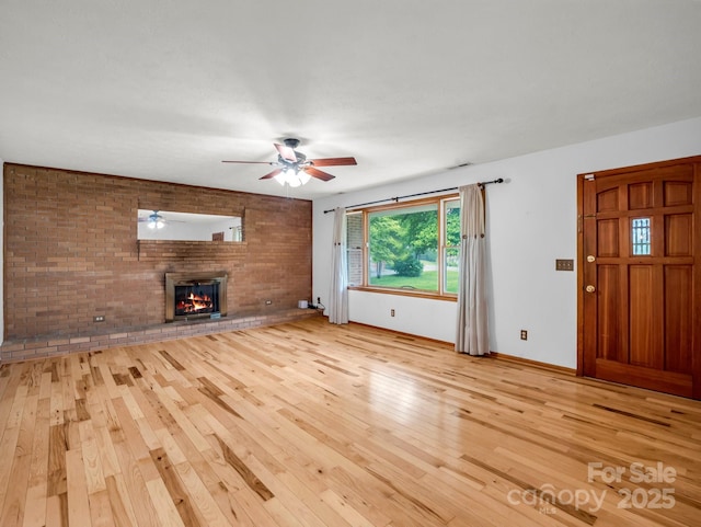 989 Mine Gap Rd, Zirconia, NC 28790 - unfurnished living room with light wood-type flooring, a ceiling fan, a fireplace, baseboards, and brick wall