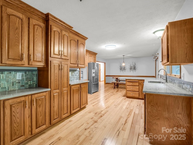989 Mine Gap Rd, Zirconia, NC 28790 - kitchen with stainless steel refrigerator with ice dispenser, a sink, brown cabinetry, a peninsula, and a textured ceiling