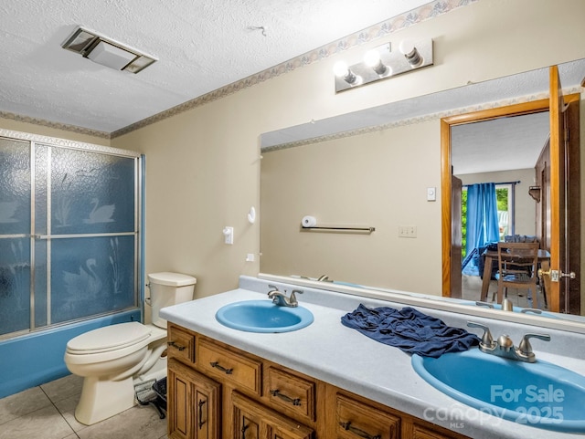 989 Mine Gap Rd, Zirconia, NC 28790 - full bath featuring double vanity, toilet, a textured ceiling, tile patterned flooring, and enclosed tub / shower combo