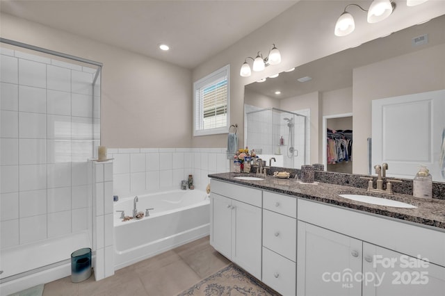 608 Latrobe Dr, Iron Station, NC 28080 - bathroom featuring a stall shower, double vanity, tile patterned flooring, a bath, and a spacious closet