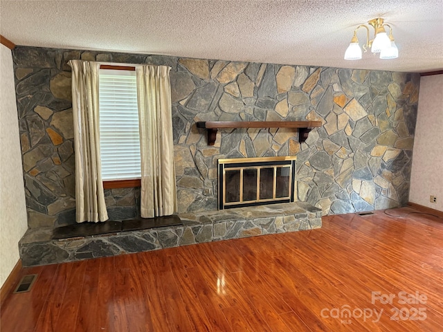 6018 Unionville Rd, Monroe, NC 28110 - detailed view of wood finished floors, a textured ceiling, a stone fireplace, and baseboards