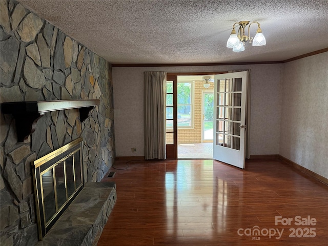 6018 Unionville Rd, Monroe, NC 28110 - unfurnished living room with a textured ceiling, hardwood / wood-style flooring, ornamental molding, a stone fireplace, and baseboards
