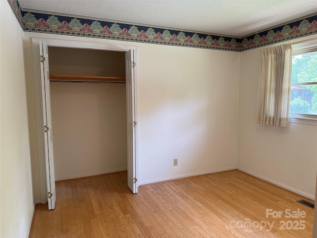 6018 Unionville Rd, Monroe, NC 28110 - unfurnished bedroom featuring light wood finished floors, baseboards, a textured ceiling, and a closet