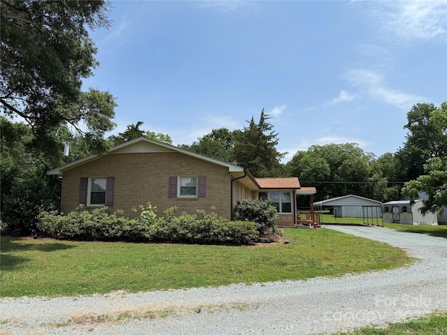 6018 Unionville Rd, Monroe, NC 28110 - view of front of house featuring gravel driveway, brick siding, a front yard, and a detached carport