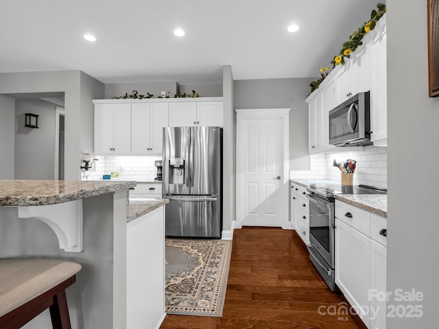 26 Balsam High Rd, Biltmore Lake, NC 28715 - kitchen featuring appliances with stainless steel finishes, white cabinets, tasteful backsplash, a kitchen bar, and recessed lighting
