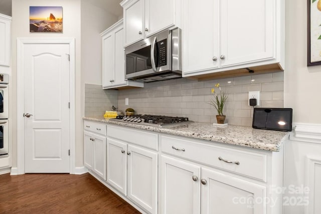 1467 Tranquility Blvd, Lancaster, SC 29720 - kitchen featuring stainless steel appliances, white cabinetry, dark wood-style flooring, tasteful backsplash, and light stone countertops